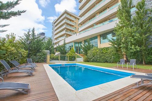 a swimming pool with chairs and a building at Albar Club de Mar in Pinamar