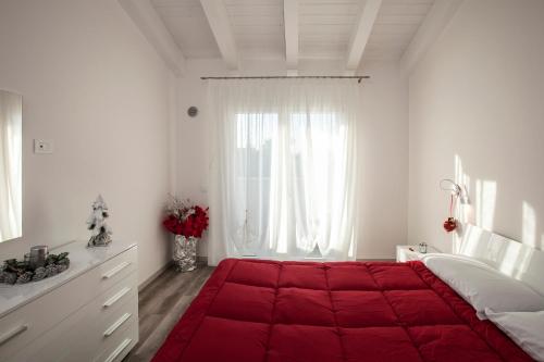a white bedroom with a large red bed in front of a window at Albergo Antica Corte Marchesini in Campagna Lupia