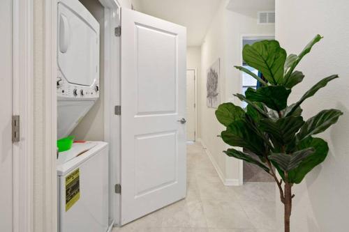 La salle de bains est pourvue d'une porte blanche et d'une plante. dans l'établissement Luxury 2BR condo with 2 Clubhouses, à Kissimmee