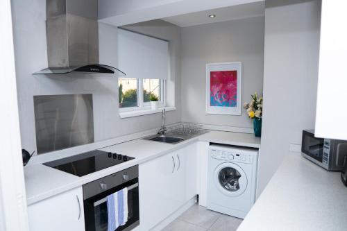 a white kitchen with a sink and a washing machine at Luke Stays - Front Street in Newcastle upon Tyne