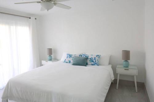 a white bedroom with a bed and a ceiling fan at Sea Glass Villa - Spacious 1 Bed, 2 Bath on West Coast in Saint James