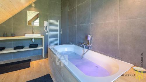 un ampio bagno con grande vasca e lavandino di Chalet des Marmottes a Besse-et-Saint-Anastaise