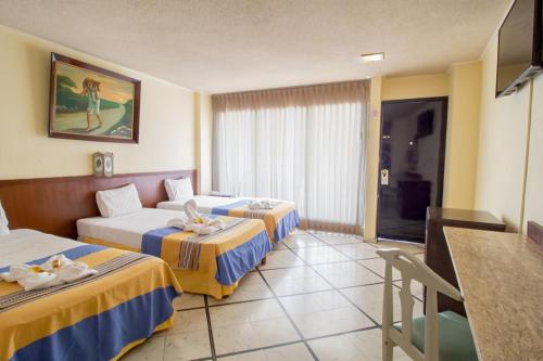 a hotel room with two beds and a table at Hotel Ambassador Mérida in Mérida