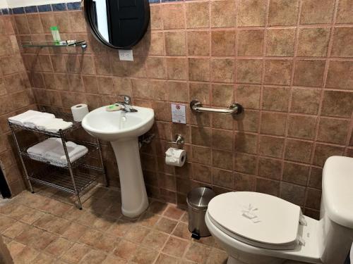 uma casa de banho com um lavatório, um WC e um espelho. em La Sirena Playa Jacó em Jacó