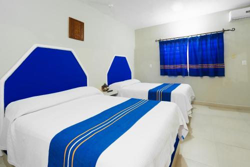 two beds in a room with blue and white at Hotel Yumkiin - Cerca Del Ferry y Terminal ADO in Playa del Carmen