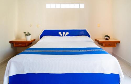 a blue and white bed in a room with two tables at Hotel Yumkiin - Cerca Del Ferry y Terminal ADO in Playa del Carmen