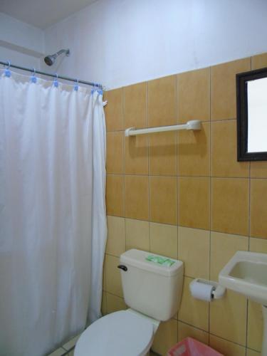 a bathroom with a white shower curtain and a toilet at Hotel Quinta Avenida in San José