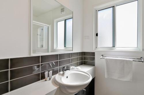 a white bathroom with a sink and two windows at Kaloha Holiday Resort Phillip Island in Cowes