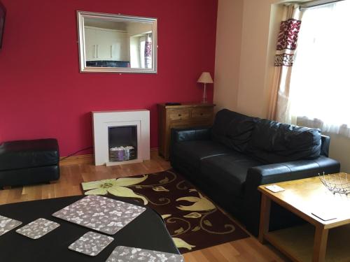 a living room with a black couch and a red wall at Ground floor 2 bed apartment in central location with private access to 7 miles of sandy beach (sleeps 4) in Brean