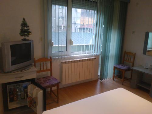 a living room with a tv and two chairs and a window at Hotel Tsarevets in Asenovgrad