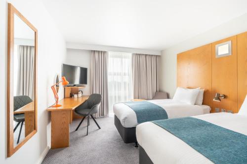 a hotel room with two beds and a desk at Holiday Inn Bournemouth by IHG in Bournemouth