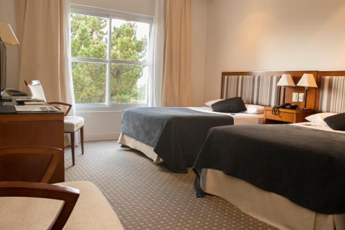 a hotel room with two beds and a window at Elegance Hotel Tandil in Tandil