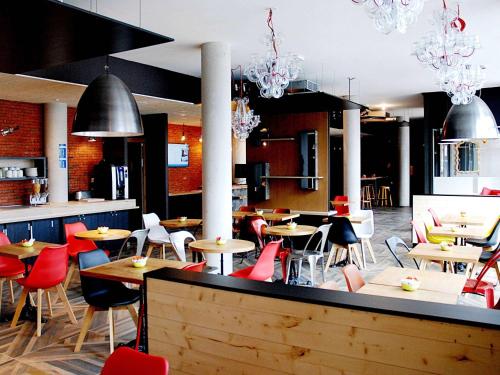 a restaurant with tables and chairs and chandeliers at Ibis Budget Annecy sud-Poisy in Poisy