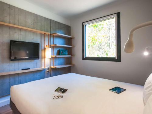 een kamer met een bed, een tv en een raam bij ibis budget Château-Thierry in Essômes-sur-Marne