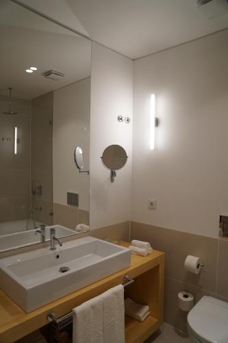 a bathroom with a sink and a mirror and a toilet at Flora Baixa Apartments in Lisbon