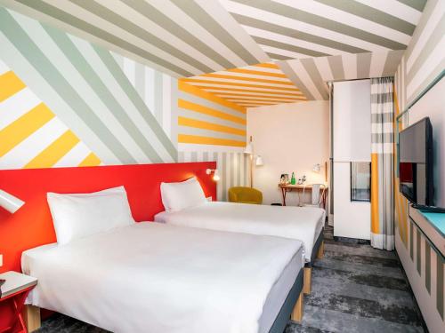 two beds in a hotel room with striped ceilings at ibis Styles Warszawa Centrum in Warsaw