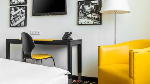 a room with a desk and a chair and a tv at Holiday Inn Munich - Westpark by IHG in Munich