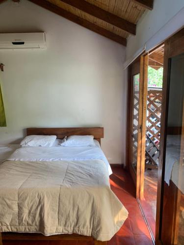 a bedroom with a bed and a door to a balcony at Villa Mistika in Zorritos