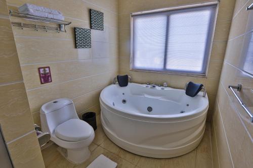a bathroom with a tub and a toilet and a window at Hotel Essencia in Dumaguete