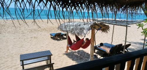 a person laying in a hammock on a beach at Ganesh Garden Beach Cabanas in Tangalle