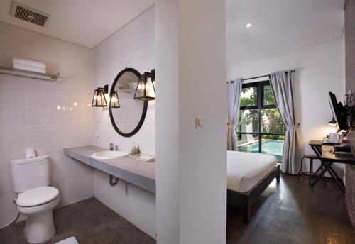 a bathroom with a sink and a toilet and a mirror at The Aswana Seminyak in Seminyak