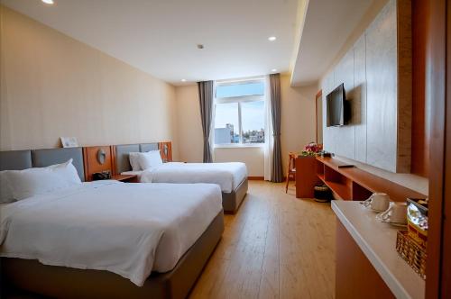 a hotel room with two beds and a television at Bella Vita Hotel in Long Hai