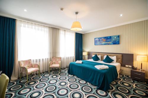 アルマトイにあるMildom Hotelのベッド1台と椅子2脚が備わるホテルルームです。
