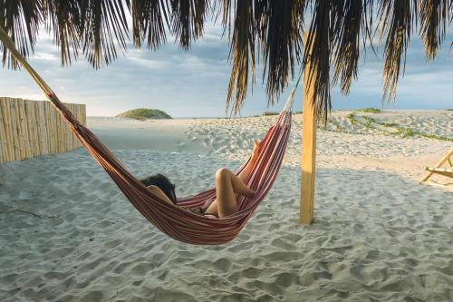 a woman laying in a hammock on a beach at Vistazul in Vichayito