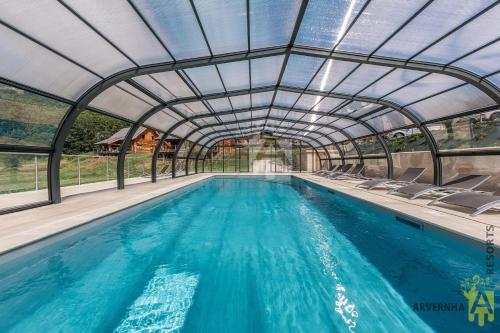 une piscine intérieure avec un toit rétractable dans l'établissement Chalets de Fougerousse, à Chambon-sur-Lac