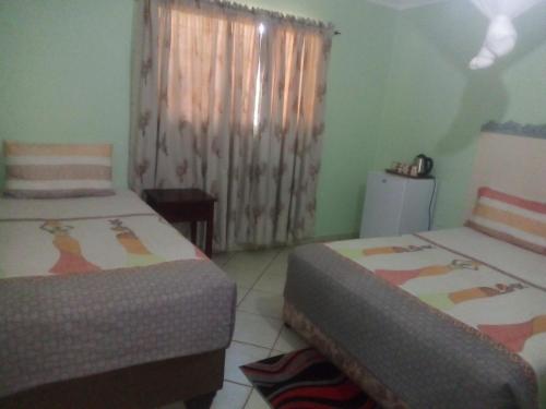 a bedroom with two beds and a window with curtains at Gloria's Bed and Breakfast in Livingstone