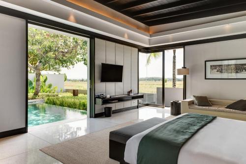 a bedroom with a bed and a tv and a pool at Soori Bali in Tabanan