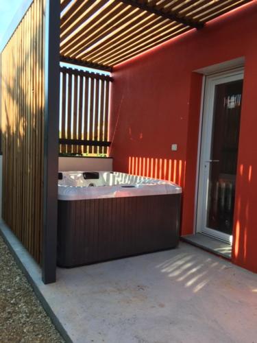 a red building with a hot tub on the side of it at Les Lodges - Villa avec spa privatif in Valensole