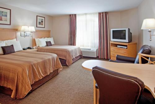 ein Hotelzimmer mit 2 Betten und einem TV in der Unterkunft Candlewood Suites Junction City - Ft. Riley, an IHG Hotel in Junction City