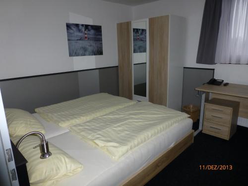 a bedroom with a bed and a sink and a desk at Hotel Rüstersieler Hof in Wilhelmshaven