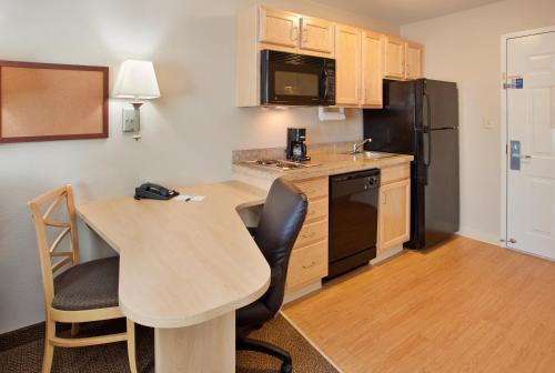 a small kitchen with a table and a black refrigerator at Candlewood Suites Junction City - Ft. Riley, an IHG Hotel in Junction City