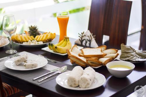 a table topped with plates of food and bread at White Land City Hotel in Dambulla