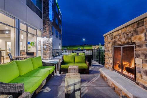 a patio with a green couch and a fireplace at Holiday Inn Express & Suites - Rice Lake by IHG in Rice Lake