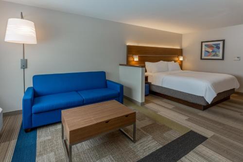 une chambre d'hôtel avec un lit et un canapé bleu dans l'établissement Holiday Inn Express & Suites - Rice Lake, an IHG Hotel, à Rice Lake