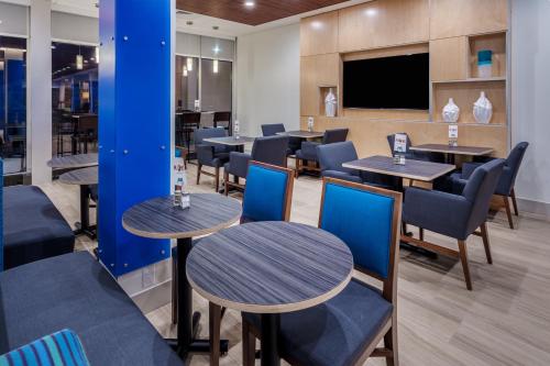 a restaurant with tables and chairs and a flat screen tv at Holiday Inn Express & Suites - Rice Lake by IHG in Rice Lake