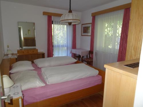 a bedroom with a bed with white pillows and a mirror at Haus Sabina in Siusi