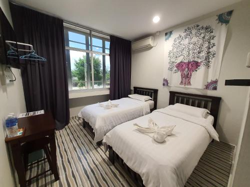 a hotel room with two beds and a window at De' Chukai Hotel in Kemaman