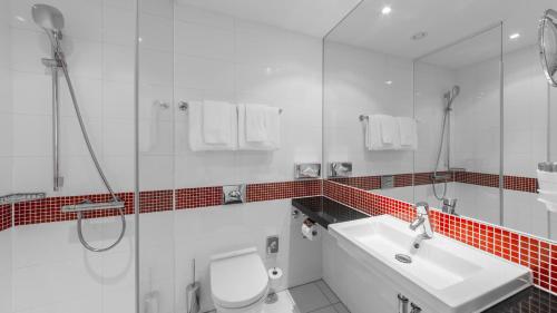 a bathroom with a toilet and a sink and a shower at Holiday Inn Munich - Leuchtenbergring by IHG in Munich