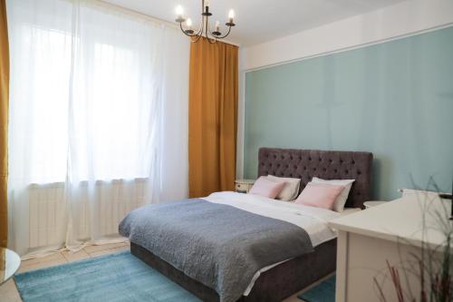a bedroom with a bed with pink pillows on it at Color Apartments Eugen Carada St in Bucharest