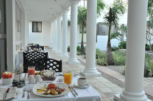 a table with a plate of food on a porch with palm trees at Premier Hotel The Richards in Richards Bay