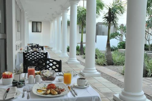 einen Tisch mit einem Teller Essen auf einer Veranda mit Palmen in der Unterkunft Premier Hotel The Richards in Richards Bay