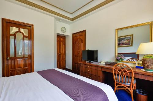 a bedroom with a bed and a desk with a television at The Spring Hotel in Ho Chi Minh City