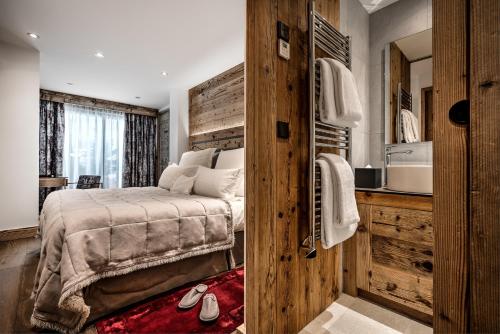 a bedroom with a bed with a wooden wall at Hôtel La Sivolière in Courchevel