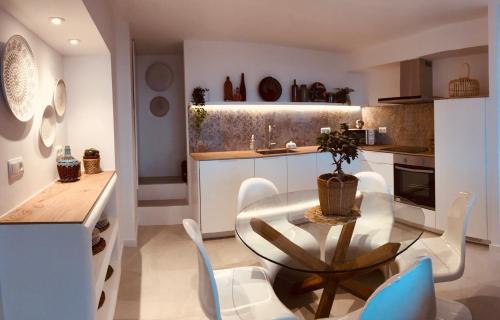 a kitchen with a glass table and white chairs at Can Estrellas apartamento vista mar in Begur