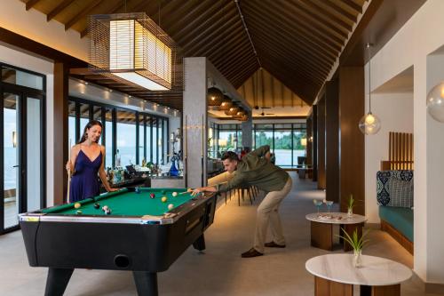 a man and a woman playing a game of pool at Pullman Maldives Maamutaa - All-Inclusive Resort - 50 percent off Transfers in Maamutaa
