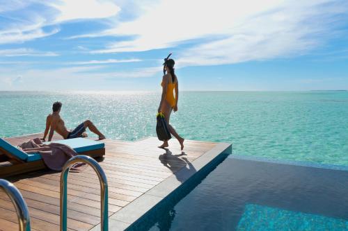 a man and a woman standing on a dock near the ocean at Pullman Maldives Maamutaa - All-Inclusive Resort - 50 percent off Transfers in Maamutaa
